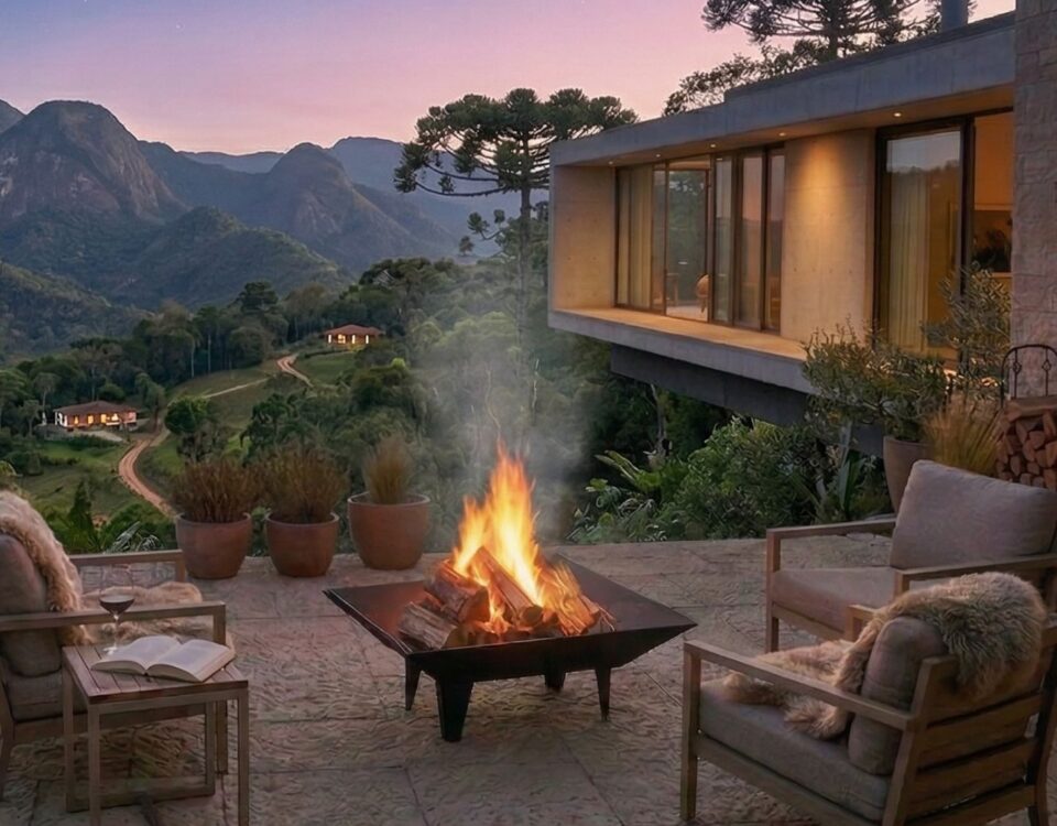 braseiro mf quad fire 1 20260331135102 3aab2cd506d2 Terraço ao ar livre com lareira acesa, cadeiras aconchegantes e vista de montanhas ao pôr do sol.