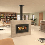 Sala de estar ampla em plano aberto com lareira central embutida em uma parede divisória, estante de livros ao fundo, área de leitura com poltronas, e ilha de cozinha com banquetas, tudo iluminado por luz suave.